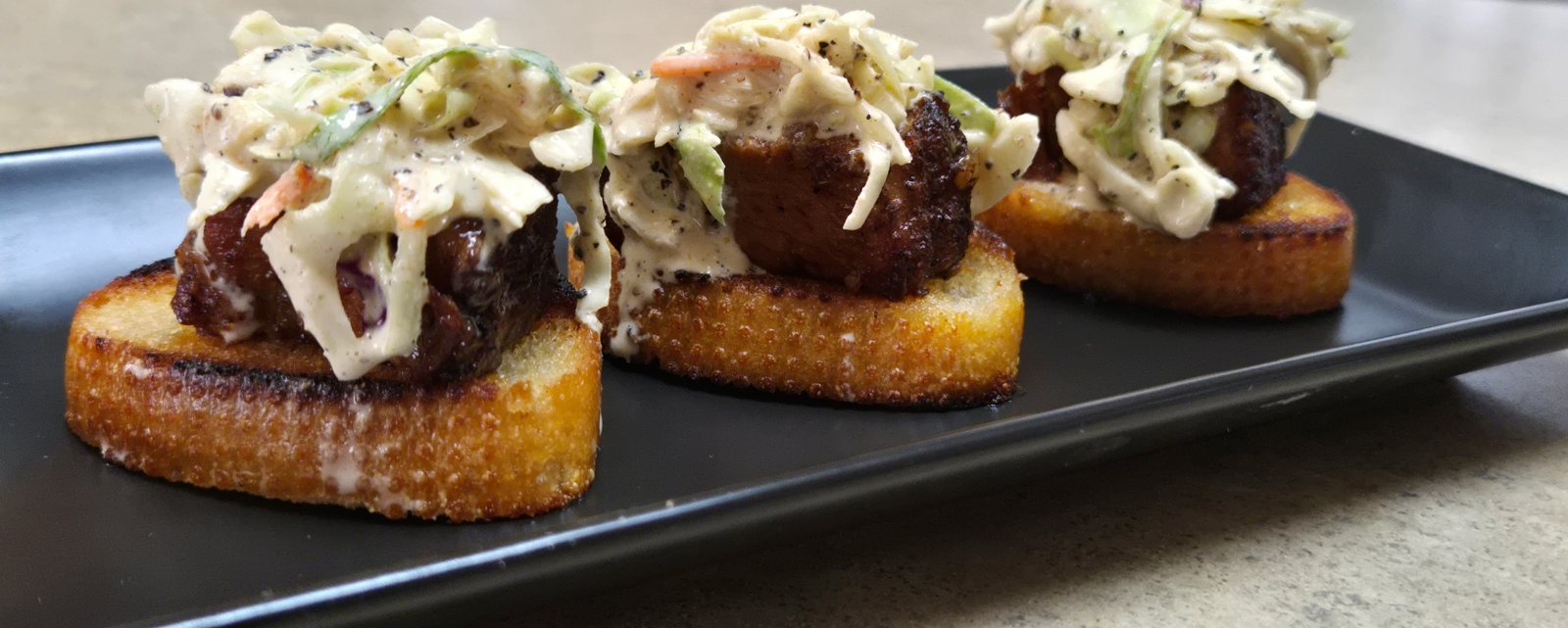 Pork Belly Burnt End Crostini with Spicy Beer Mustard Slaw